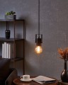 Nad stołem lampa wisząca CALARI emituje ciepłe światło z odsłoniętej żarówki, podkreślając czarną metalową formę oprawy.