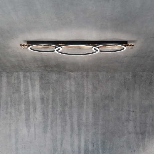 Lampa sufitowa LED BOYAL 3x12W z drewnianym korpusem i trzema owalnymi pierścieniami świetlnymi, zamontowana na suficie i emitująca ciepłe białe światło 3000K.