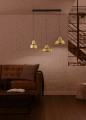 Lampa wisząca SAVARNA z trzema złotymi kloszami rozmieszczonymi w jednej linii, zawieszona nad strefą wypoczynkową na czarnych przewodach.