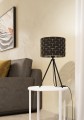 Na jasnym stoliku lampa stołowa MARASALES prezentuje czarny abażur z geometrycznym wzorem oraz charakterystyczną trójnożną konstrukcję podstawy.