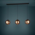 Lampa wisząca CORDOBA z trzema szklanymi kloszami w miedzianym wykończeniu, zawieszona na czarnych przewodach i emitująca ciepłe światło.