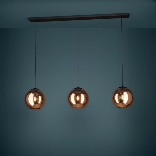 Lampa wisząca CORDOBA z trzema szklanymi kloszami w miedzianym wykończeniu, zawieszona na czarnych przewodach i emitująca ciepłe światło.