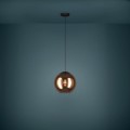 Lampa wisząca CORDOBA z miedzianym szklanym kloszem na czarnym przewodzie, zawieszona na tle niebieskiej ściany.