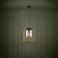 Lampa wisząca CAMINATA z pojedynczym transparentnym szklanym kloszem, zawieszona na czarnym przewodzie i emitująca ciepłe światło.