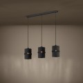 Lampa wisząca PARAGUAIO z trzema czarnymi kloszami, zawieszona w jednej linii i emitująca ciepłe światło na ścianę.