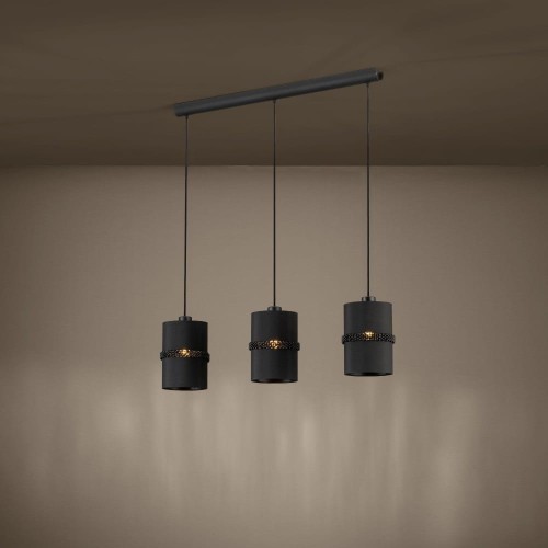 Lampa wisząca PARAGUAIO z trzema czarnymi kloszami, zawieszona w jednej linii i emitująca ciepłe światło na ścianę.
