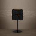 Lampa stołowa PARAGUAIO z czarnym cylindrycznym kloszem, ustawiona na smukłej podstawie i emitująca ciepłe światło.