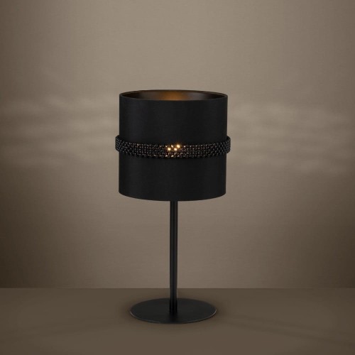 Lampa stołowa PARAGUAIO z czarnym cylindrycznym kloszem, ustawiona na smukłej podstawie i emitująca ciepłe światło.