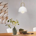 Lampa wisząca CALMANERA z białym metalowym kloszem i mosiężnym detalem, zawieszona nad stołem w jasnym wnętrzu.