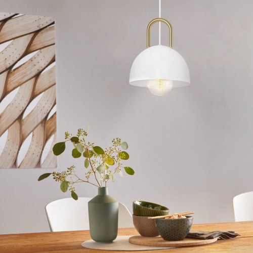 Lampa wisząca CALMANERA z białym metalowym kloszem i mosiężnym detalem, zawieszona nad stołem w jasnym wnętrzu.