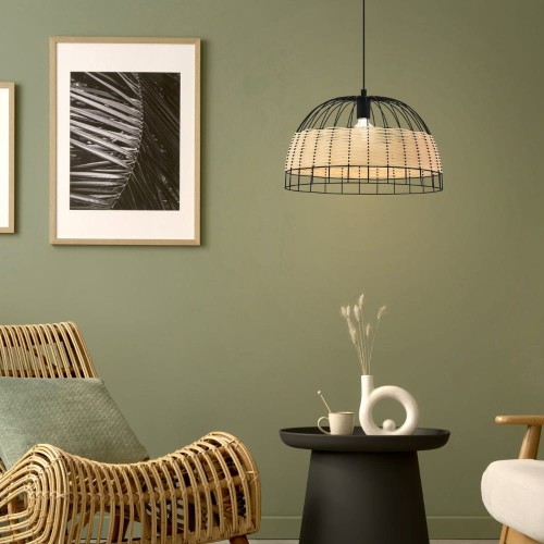 Lampa wisząca ANWICK z półokrągłym kloszem z naturalnego rattanu i czarnego metalu, zawieszona nad stołem w salonie z zieloną ścianą.