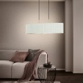 Lampa wisząca TAMARESCO z podłużnym białym aksamitnym kloszem i złotymi detalami, zawieszona nad stolikiem w eleganckim salonie.