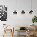 Lampa wisząca OILELLA z trzema kulistymi kloszami z przyciemnianego szkła w czarno-szarym odcieniu, zawieszona nad drewnianym stołem w jasnej jadalni.