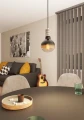 Lampa wisząca YORTH ze srebrną metalową oprawką i odsłoniętą żarówką E27, zawieszona nad stolikiem i emitująca ciepłe światło.