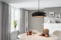 Lampa wisząca MOGANO 1 z czarnym metalowym kloszem i złotym wnętrzem, zawieszona na długim przewodzie nad stołem, z widocznym światłem skierowanym w dół.