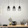 Lampa wisząca MILLIGAN z trzema cylindrycznymi kloszami z czarnej metalowej siatki i białymi elementami, zawieszona nad blatem kuchennym.