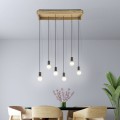 Lampa wisząca WOOTTON z prostokątną drewnianą podsufitką i sześcioma czarnymi przewodami zakończonymi żarówkami, zawieszona nad stołem w jasnej jadalni.