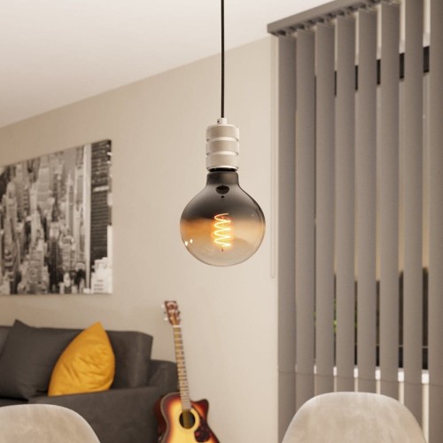 Lampa wisząca YORTH z metalową oprawką w srebrnym wykończeniu, zawieszona na czarnym przewodzie nad stolikiem w nowoczesnym wnętrzu.