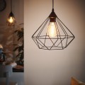 Lampa wisząca TARBES z czarnym metalowym kloszem o geometrycznej, ażurowej konstrukcji, zawieszona w nowoczesnym wnętrzu z widoczną żarówką E27.