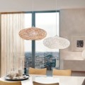 Lampa wisząca CAMPILO z szerokim, spłaszczonym kloszem wykonanym z białych papierowych nici, zawieszona nad stołem w jasnym wnętrzu.