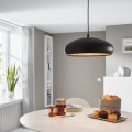 Lampa wisząca MOGANO 1 z szerokim czarnym metalowym kloszem o półkulistym kształcie i złotym wnętrzu, zawieszona nad stołem w jasnej jadalni.