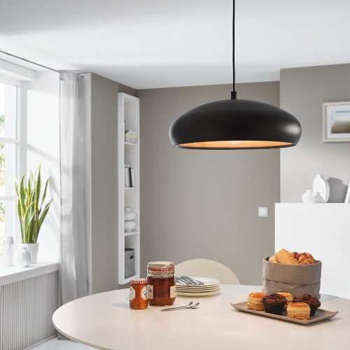 Lampa wisząca MOGANO 1 z szerokim czarnym metalowym kloszem o półkulistym kształcie i złotym wnętrzu, zawieszona nad stołem w jasnej jadalni.