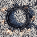 Girlanda ogrodowa z czarnym przewodem i żarówkami G45 LED 1,5W 2100K Soft Glow, ułożona w krąg na tle jasnych kamieni. Żarówki świecą ciepłym światłem, osadzone w czarnych oprawkach.