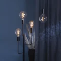 Dekoracyjne żarówki LED filament ze spiralnym filamentem LED zamontowane w nowoczesnej czarnej lampie podłogowej. Ciepłe światło żarówek tworzy nastrojową atmosferę we wnętrzu.