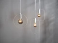 Designerskie lampy wiszące z dekoracyjnymi żarówkami LED i metalowymi ramkami na jasnym tle.