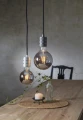 Dwie wiszące lampy z dekoracyjnymi żarówkami LED nad drewnianym stołem z dodatkami i świecą w minimalistycznym wnętrzu.