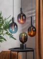 Dekoracyjne żarówki LED E27 w różnych kolorach szkła zawieszone nad stolikiem, elegancka aranżacja wnętrza z zasłoną i rośliną.