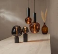 Dekoracyjne żarówki LED filament w przydymionym i bursztynowym szkle zawieszone oraz ustawione na czarnych lampach nad drewnianym stołem. Designerskie oświetlenie emitujące ciepłe światło do nowoczesnych wnętrz.