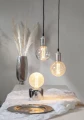 Dekoracyjne lampy z żarówkami LED filament G125 w oprawach wiszących oraz lampie stołowej w jasnym wnętrzu.