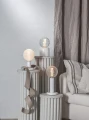 Aranżacja wnętrza z dekoracyjnymi lampami i żarówkami LED filament G125 ustawionymi na podestach obok sofy.