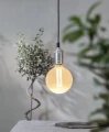 Wisząca lampa z kulistą żarówką LED filament G125 świecącą ciepłym białym światłem w aranżacji wnętrza.