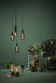 Trzy wiszące lampy z dekoracyjnymi żarówkami LED filament w ryflowanych kloszach nad stołem w nowoczesnym wnętrzu.