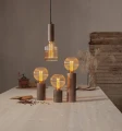 Aranżacja stołu z dekoracyjnymi lampami i żarówkami LED filament w ryflowanych bursztynowych kloszach ustawionych na drewnianych podstawach.