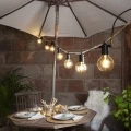 Girlanda ogrodowa z żarówkami LED filament E27 G95 amber, ciepłe światło dekoracyjne nad stołem na tarasie, klimatyczna aranżacja wieczorna.