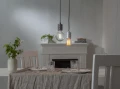 Dwie wiszące lampy z dekoracyjnymi żarówkami LED filament nad stołem w jadalni, przytulna aranżacja wnętrza.