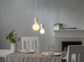 Dwie wiszące lampy z żarówkami LED E27 o różnych barwach światła nad stołem w jadalni, nowoczesna aranżacja wnętrza.