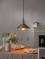 Lampa wisząca nad stołem jadalnym z ciepłym światłem żarówki LED, aranżacja wnętrza z talerzami, kieliszkami i dekoracją roślinną.