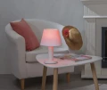 Lampa stołowa z kolorowym światłem LED na stoliku obok fotela, przytulna aranżacja wnętrza z poduszką i kominkiem.