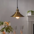 Lampa wisząca z metalowym kloszem i ciepłym światłem LED nad stołem, elegancka aranżacja wnętrza z rośliną i zastawą stołową.