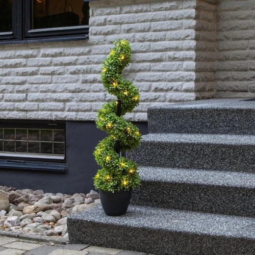 Bliski plan spiralnego bukszpanu LED na tle schodów zewnętrznych, pokazujący intensywność światła i strukturę liści.