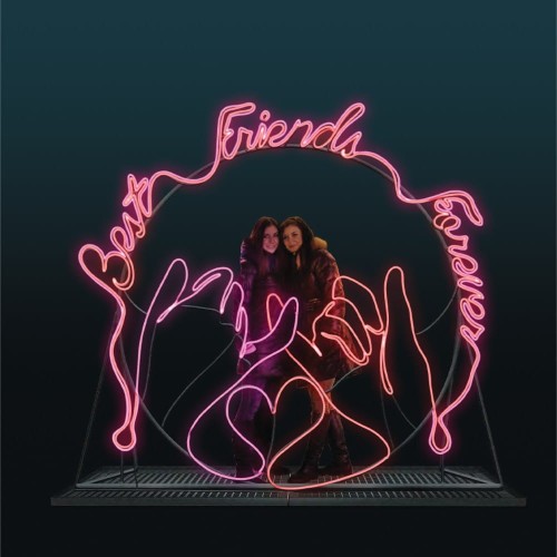 Rama świetlna LED NEON „Najlepsi Przyjaciele” w kolorze różowym, z napisem Best Friends, sercem i motywem dłoni, tworząca fotopunkt z osobami stojącymi wewnątrz konstrukcji.