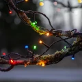 Kolorowe lampki choinkowe LED FLASHY owinięte wokół gałęzi drzewa, emitujące światło w barwach czerwonej, zielonej, niebieskiej i żółtej.
