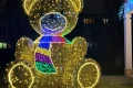 Detal świetlnej dekoracji Miś w szaliku 3D – połyskujące złote światło LED oraz kolorowy szalik w pasy nadający postaci radosny, dziecięcy charakter.