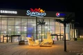 Przestrzenna dekoracja świąteczna z podświetlanymi saniami i reniferem LED ustawiona przed wejściem do kompleksu Suntago, tworząca eleganczną iluminację w strefie wejściowej nocą.
