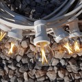 Girlanda ogrodowa z białym przewodem i żarówkami G45 LED 1,5W 2100K Soft Glow, ułożona na tle jasnych kamieni. Żarówki w przezroczystych bańkach świecą ciepłym, dekoracyjnym światłem.