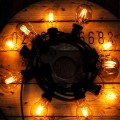 Girlanda ogrodowa z żarówkami LED A60 z serii Soft Glow 1,5W 2100K, ułożona w krąg na drewnianej szpuli, emitująca miękkie, ciepłe światło – idealna do dekoracji zewnętrznych.